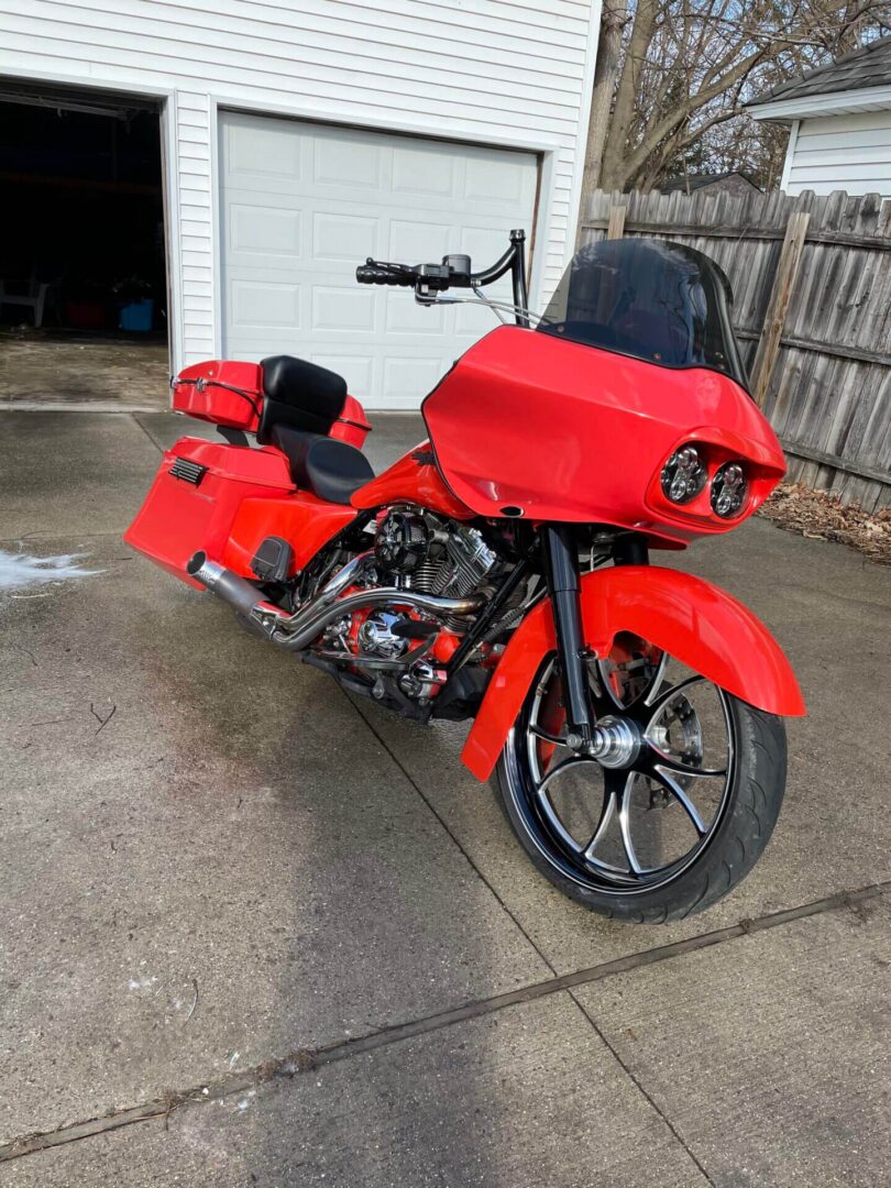 A red motorcycle parked in front of a garage.