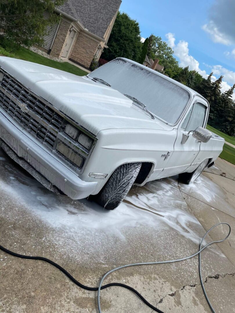 A white truck is washing in the driveway.