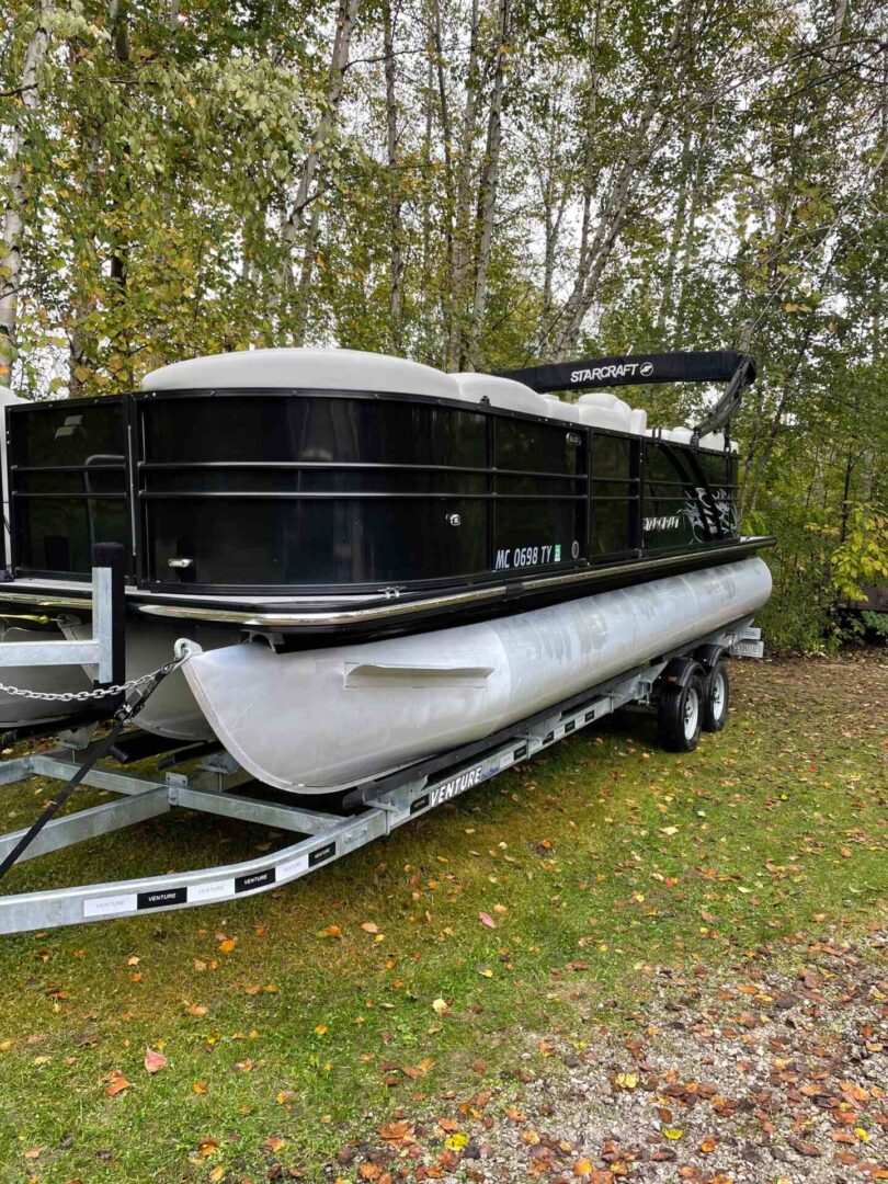 A boat is parked on the trailer in the woods.
