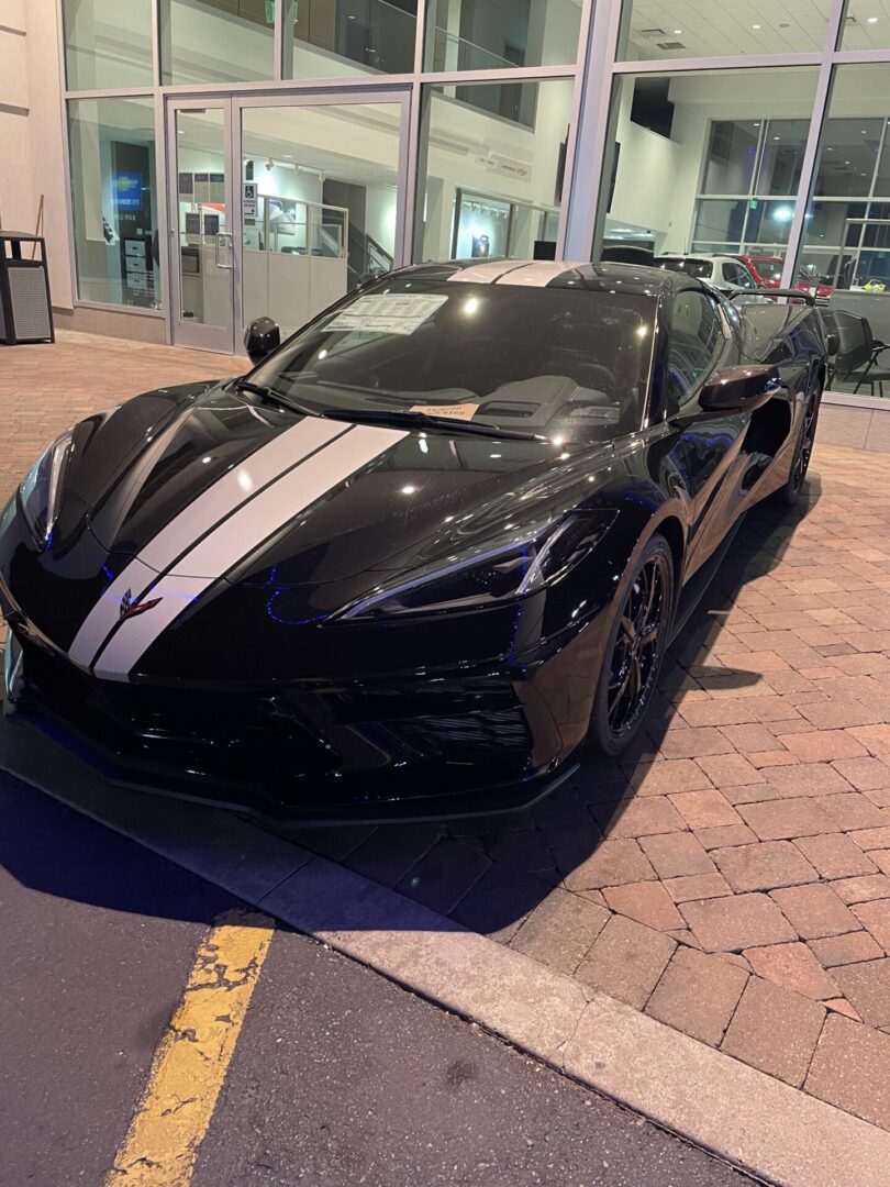 A black sports car parked in front of a building.