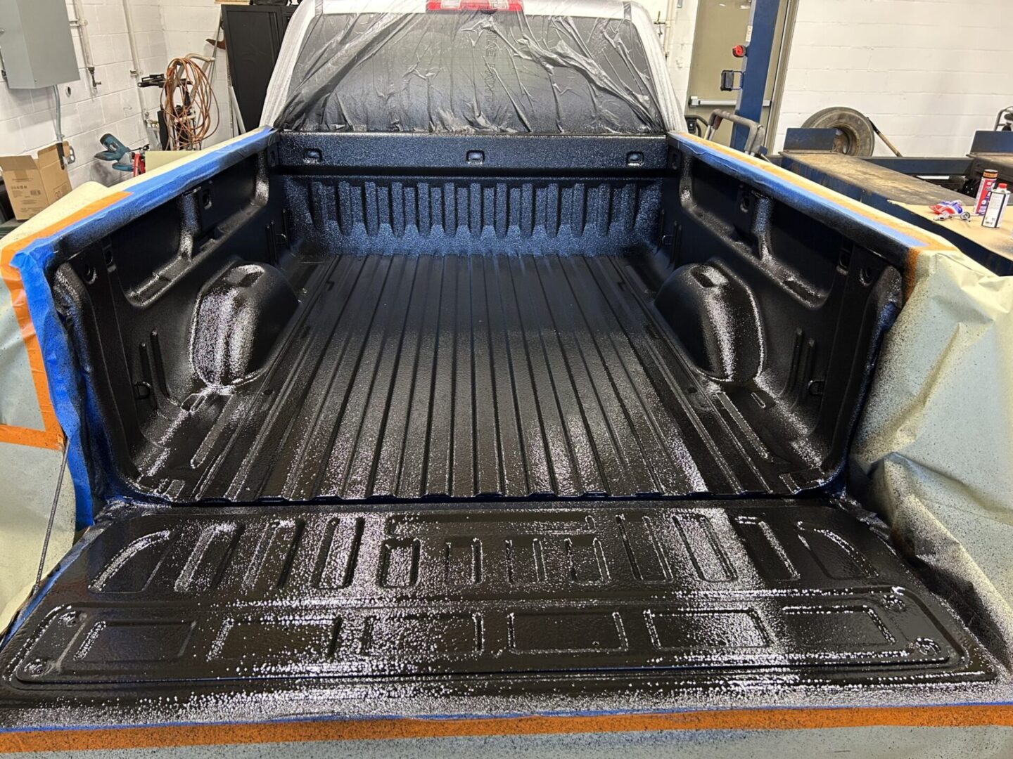 A truck bed with the liner being painted black.